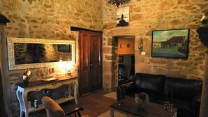 A stone-walled room with a wooden cabinet, a mirror, a sofa, and a coffee table.