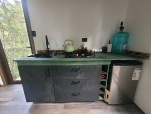 A kitchen with a gas stove, a kettle, a water dispenser, and a refrigerator. - Komorebi Lodge | River, forest, clay tub, breakfast, transportation. All-inclusive (Huililco)