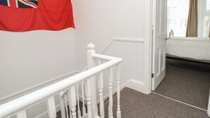 A staircase with white balusters leading to a bedroom with a bed and a window. - Bay Tree Cottage (Shanklin)