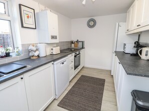 A compact kitchen with white cabinets, a toaster, a kettle, and a microwave. - Bay Tree Cottage (Shanklin)