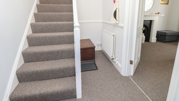 A staircase with patterned carpet, a radiator, a mirror, and a small wooden box. - Bay Tree Cottage (Shanklin)