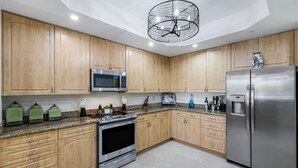Eine Küche mit Holzausstattung, einem Edelstahlkühlschrank, einer Mikrowelle und einem eingebauten Backofen.