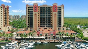 A multi-story hotel with a central tower, surrounded by smaller buildings, and a marina with boats.