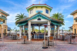 A restaurant with outdoor seating, a bar, and a thatched roof structure. - Townhouse in Cape Harbour- Sleeps 8 (Cape Coral)