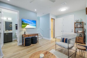 Een moderne woonkamer met een flatscreen televisie, een houten salontafel, een comfortabele fauteuil en een trap naar een andere kamer.