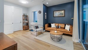 Una sala de estar moderna con sofá, sillón, mesa de centro y estantería.