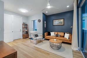 A modern living room with a sofa, armchair, coffee table, and a bookshelf. - Townhouse in Cape Harbour- Sleeps 8 (Cape Coral)