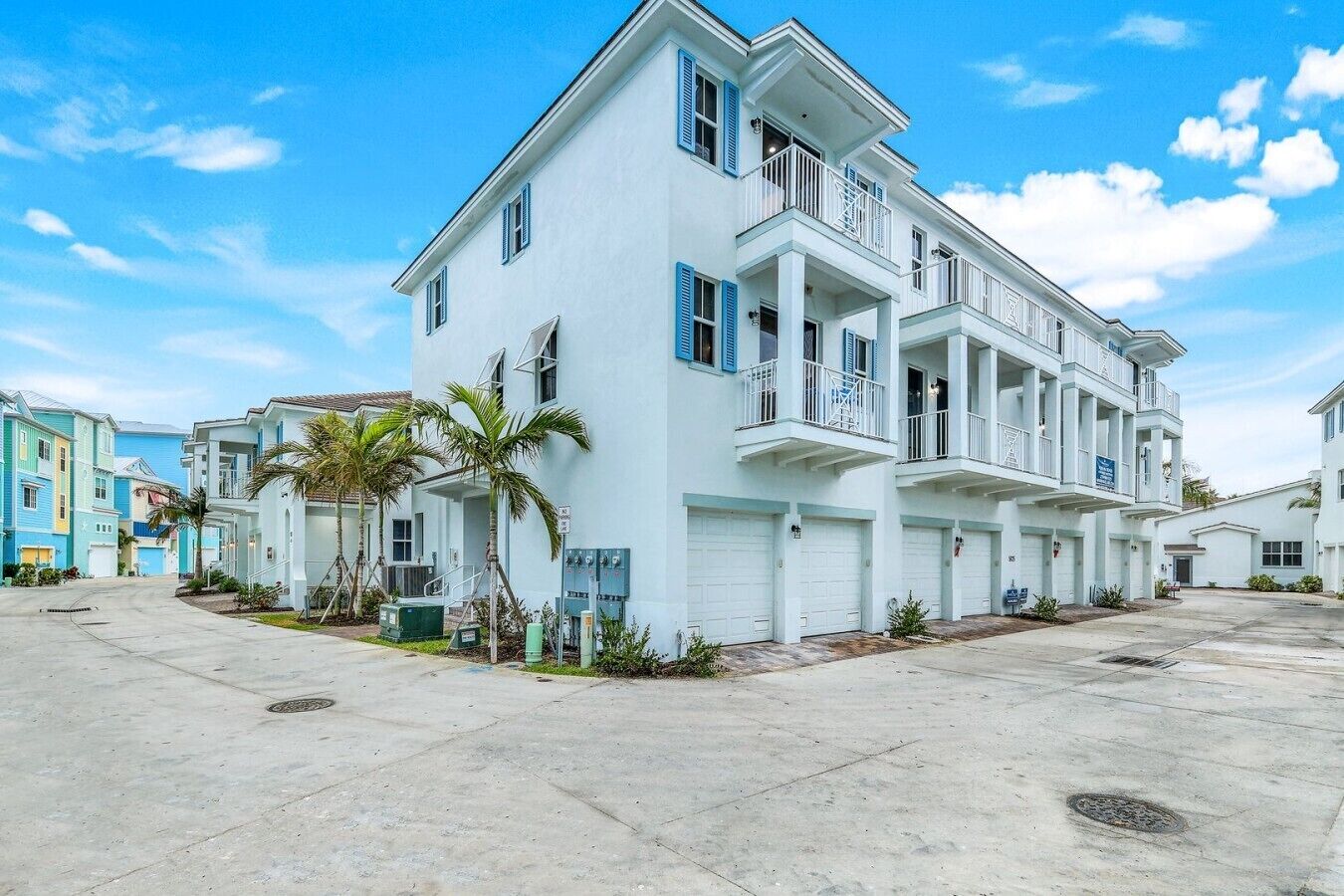 Um edifício residencial com vários andares, varandas, garagem e céu claro.