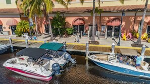 A marina with boats docked, a building with a tiled roof, and palm trees. - Townhouse in Cape Harbour- Sleeps 8 (Cape Coral)
