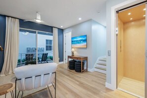 A modern room with a balcony, a sofa, a table with a lamp, and a TV on the wall. - Townhouse in Cape Harbour- Sleeps 8 (Cape Coral)