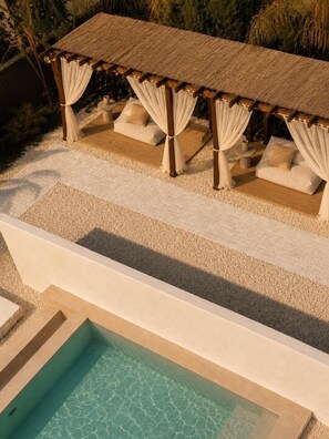 A poolside area with a covered seating area and a clear pool.