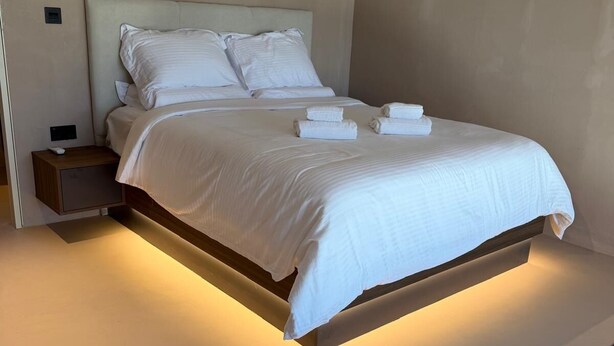 A modern hotel room with a large bed, bedside tables, and an air conditioning unit. - Leblanc Collection Mediterranean Villa 1 (Limmasol)
