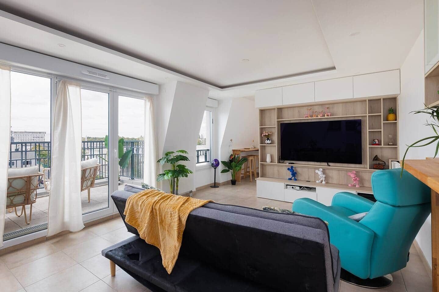 A modern living room with a sofa, a TV, and a balcony.
