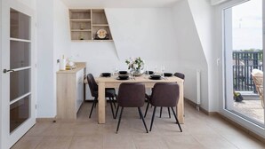Een moderne eetruimte met een houten tafel, donkere stoelen en uitzicht op het omliggende landschap door een groot raam.