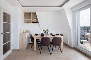Ein moderner Essbereich mit einem Holztisch, dunklen Stühlen und Blick ins Freie durch ein großes Fenster.