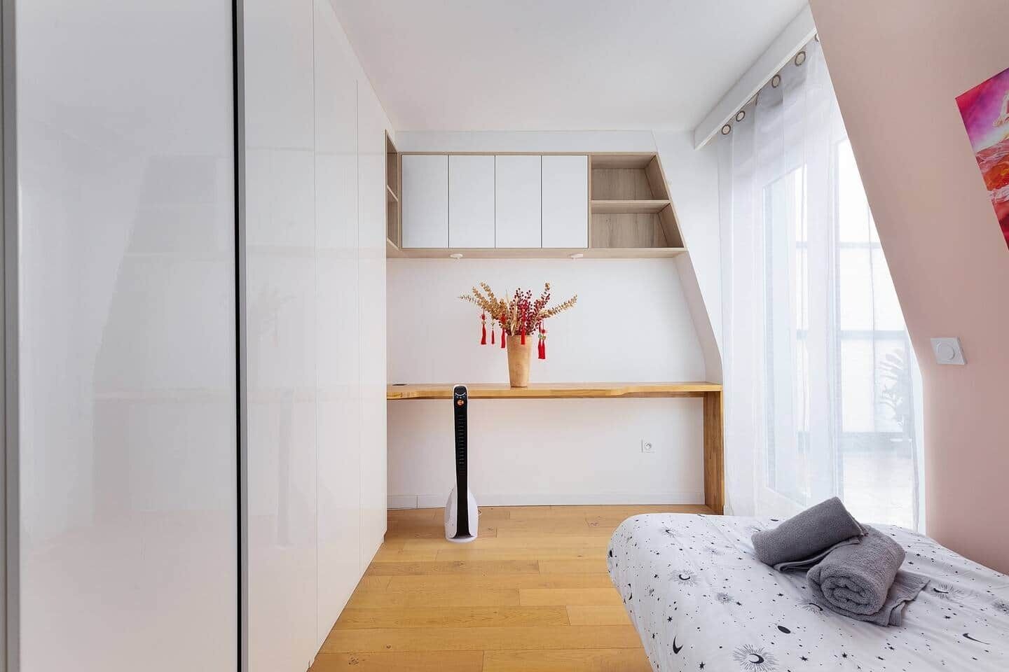 A bedroom with a bed, a desk, and a window.