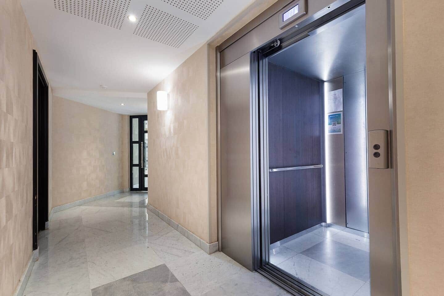A modern elevator with a metallic finish, a digital display, and a door with a handle.