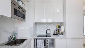 Een kleine keuken met een ingebouwde magnetron, een waterkoker en een broodrooster.