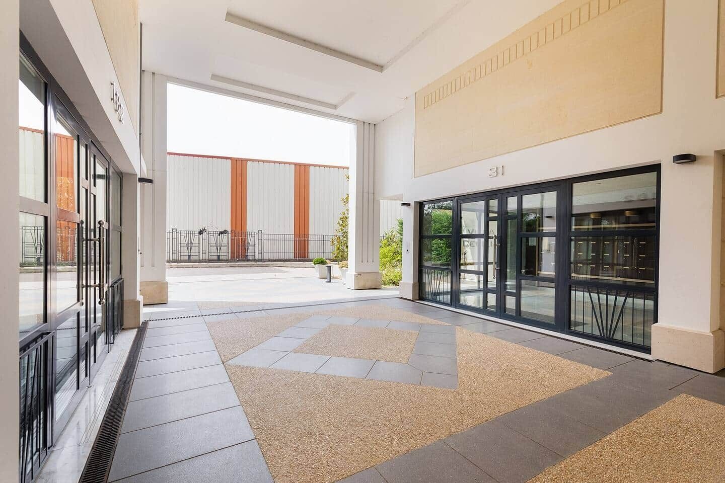 A modern hotel lobby with a tiled floor, a glass door entrance, and a view of the outside building.