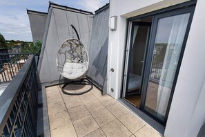 Ein Balkon mit Schaukelstuhl, einer Schiebetür und Fliesenboden.
