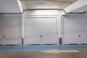 Eine Parkgarage mit drei geschlossenen Garagentoren, einer blauen Sicherheitslinie und Richtungspfeilen auf dem Boden.