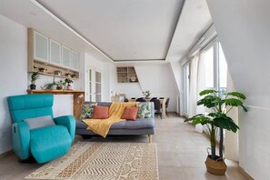 A modern living room with a sofa, armchair, and a dining area in the background. - Clamart 92 • Paris • Béclère Hospital • Tram T6/T10 (Clamart)