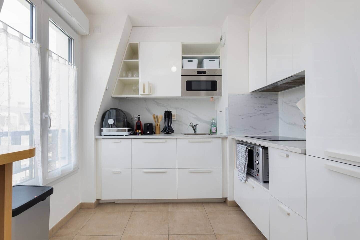 A modern kitchen with white cabinetry, a built-in oven, and a microwave.