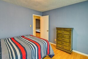 Ein Schlafzimmer mit einem Bett, einer hölzernen Kommode und einer Tür zu einem weiteren Raum.