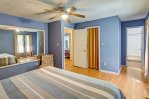 A bedroom with a bed, a ceiling fan, a door, and a hallway leading to another room. - Spacious Family Escape Near Fort Bragg & Parks (Fayetteville)