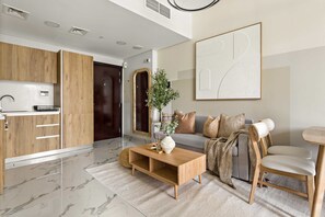 A modern living room with a wooden coffee table, a sofa, and a dining area. - Silkhaus Canal Walk 1BR Stay in Al Maryah Island (Abu Dhabi)