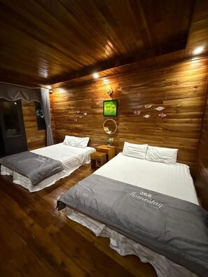 A room with wooden walls and two beds with grey bedding.