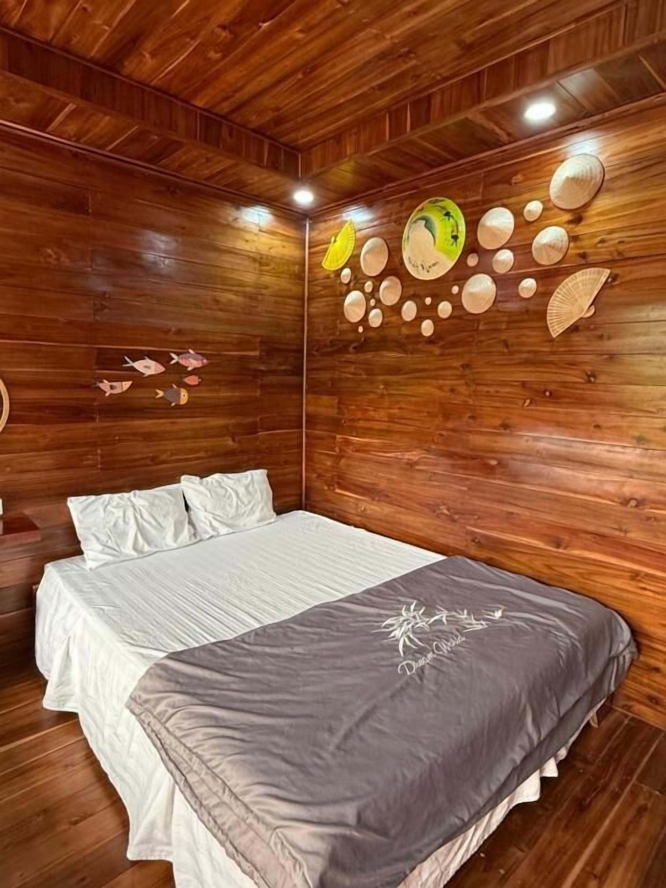 A wooden-paneled room with a bed, pillows, and a decorative wall with shells and fish.