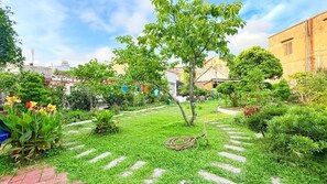 A garden with a lawn, a tree, and a hose.
