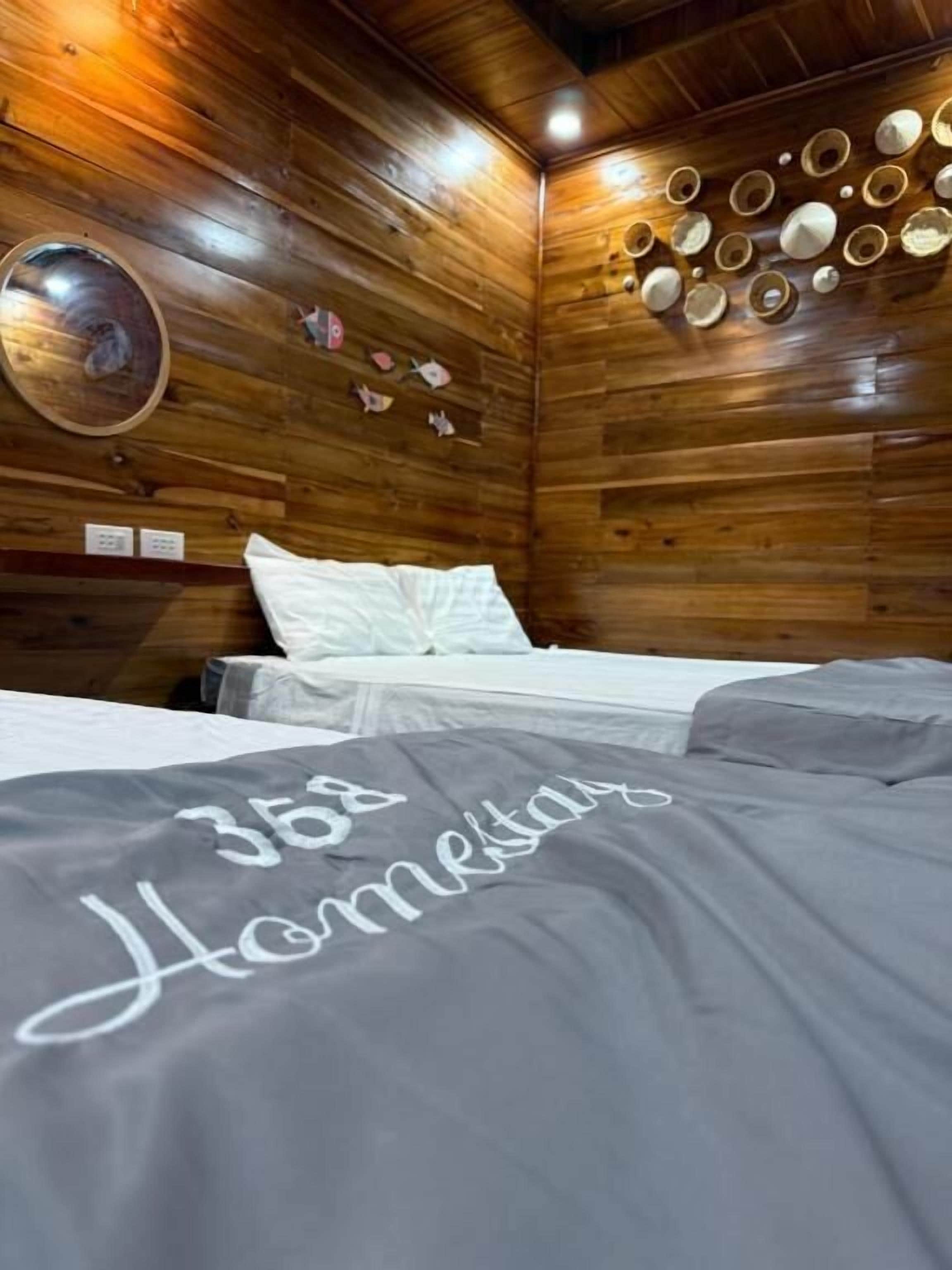 A wooden cabin-style room with a bed, a circular mirror, and a wall decorated with plates.
