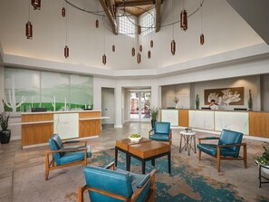 Eine geräumige Lobby mit Empfangsschalter, Sitzgelegenheiten und großen Fenstern.