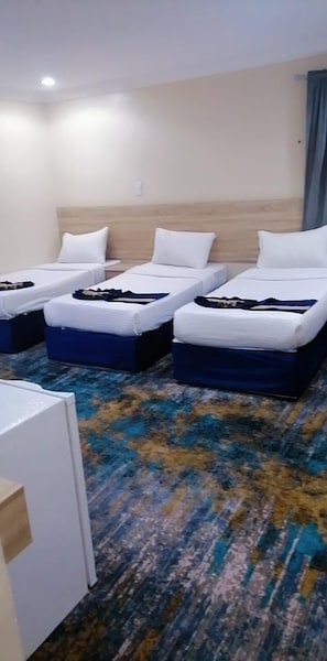 A hotel room with three single beds, a small desk, and a patterned carpet. - Sedan Hotel (Makkah)
