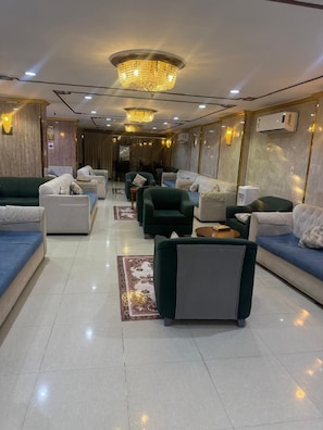 A hotel lobby with multiple seating areas, a chandelier, and air conditioning units. - Sedan Hotel (Makkah)