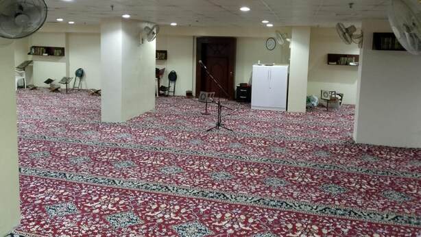 Una habitación amplia con alfombra estampada, ventiladores de techo y un atril.