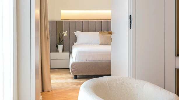 A modern bedroom with a bed, bedside table, and a nightstand with a plant. - Pearl: Luxury and Design in the Heart of Viale Ceccarini (Riccione)