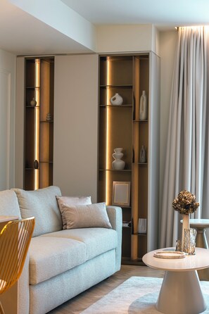 Ein modernes Wohnzimmer mit einer Couch, einem runden Couchtisch und einer hohen Regalwand mit Dekoration.