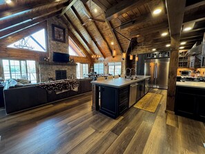 Una cocina amplia con una isla grande, vigas de madera y una pared de piedra.