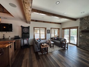 A spacious living area with a stone fireplace, wooden beams, and a large window.