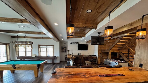 A spacious indoor area with a pool table, a bar with a unique wooden top, and a foosball table. - Luxury 7BR Lakefront Log Lodge; Sleeps 18 (DuBois)