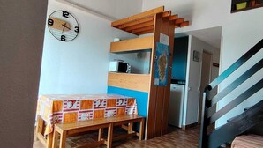 A room with a wooden table covered with a patterned tablecloth, a microwave, and a wooden staircase. - DUPLEX APART SLEEPS 5, AIR CONDITIONING, BEAUTIFUL SEA VIEW, POOL, 3 min BEACH (Grosseto-Prugna, PORTICCIO)