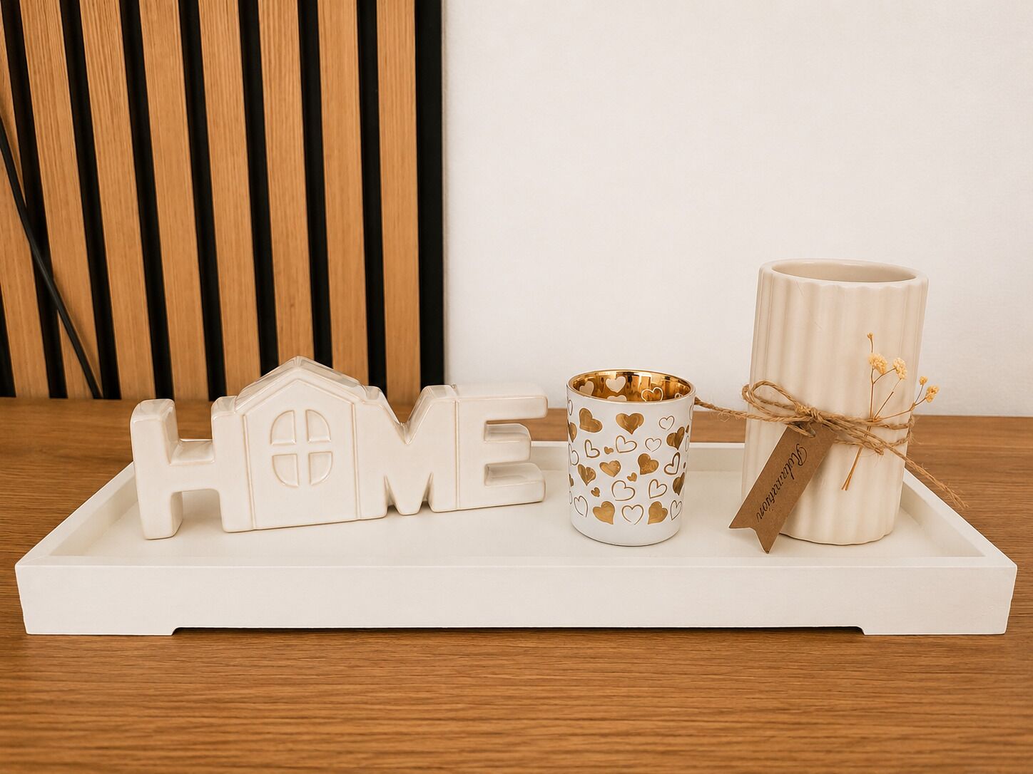 Un plateau blanc orné du mot « HOME » en lettres, une tasse blanche à motifs en forme de cœur et un porte-bougie blanc avec une étiquette.