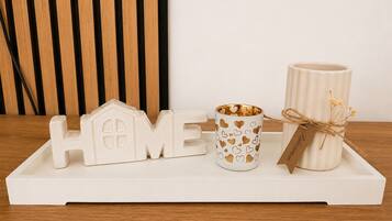 Un plateau blanc orné du mot « HOME » en lettres, une tasse blanche à motifs en forme de cœur et un porte-bougie blanc avec une étiquette.