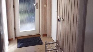 Ein Zimmer mit Tür, Fußmatte, einem Metallgestell und einer Holzwand.