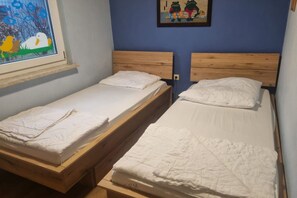 Ein Zimmer mit zwei Einzelbetten, Holz-Kopfteilen, einem Fenster mit Blick auf Enten und einem Froschgemälde.