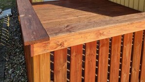 Ein Haus mit Ziegeldach, einer Holzdielen-Terrasse und einer Schiebetür aus Glas.