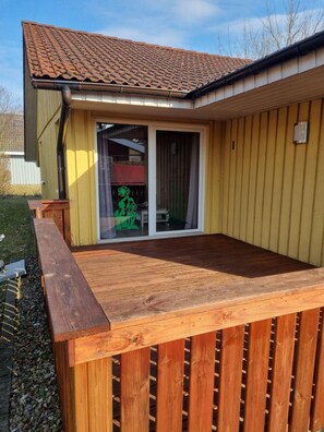 A house with a tiled roof, a wooden deck, and a sliding glass door. - Modern Eingerichteter Doppelbungalow mit Garten im Ferienpark Mirow (Mirow)